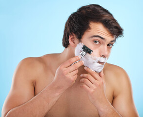Portrait, razor and man shaving with foam for hair removal, hygiene or grooming isolated on blue...