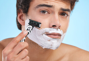 Portrait, razor and man shaving with cream for skincare, hygiene or grooming isolated on blue...