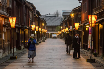 A woman is walking down a narrow street in a japanese town