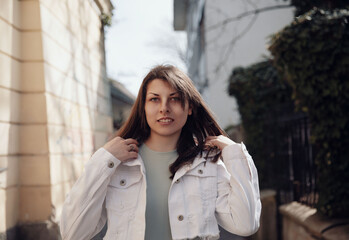 Stylish Woman in White Jacket Looking Confident on Urban Sidewalk