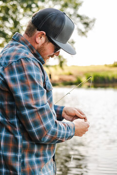 Angler attentively baiting hook by the lake.