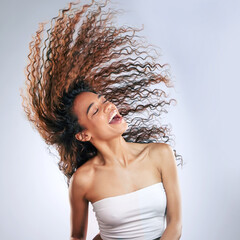 Woman, flip and hair in studio happy for healthy, volume and natural cosmetic care with treatment for curls. Girl, calm and eyes closed on white background for haircare, growth and texture for frizz.