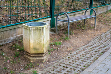 Concrete trash can and metal wooden bench.