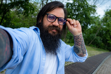 a bearded man takes a selfie on the street in sunglasses