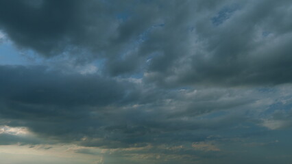 Obraz premium Summer skyscape with dark storm rain clouds on sky. Clouds against a blue sky turning into dark rain cyclones. Timelapse.