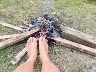 Warming feet in front campfire at outdoor background. Stock photo