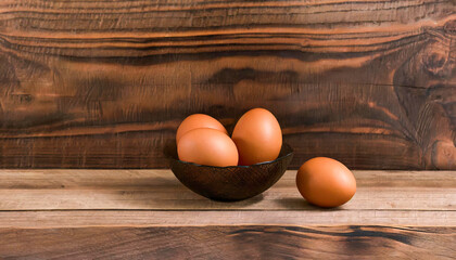 Brown eggs in a bowl on a wooden table, brown wooden background, copy space. Concept of cheap healthy source of protein. - obrazy, fototapety, plakaty