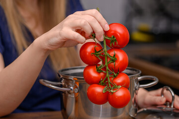 Kobieta w kuchni wkłada świeże pomidory do garnka 