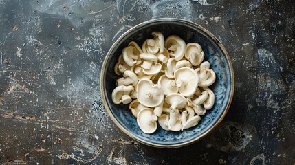 A bowl of white mushrooms on a dark table. - Powered by Adobe