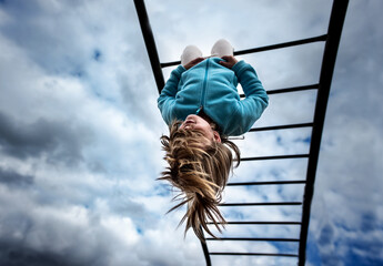 Young child hanging from monkey bars school playground