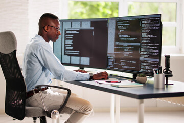 African American Coder Using Computer At Desk