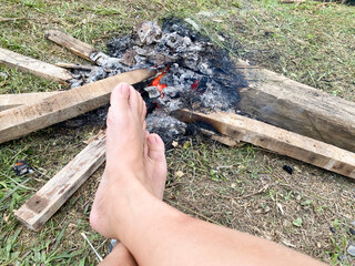 Warming feet near campfire at outdoor background. Stock photo