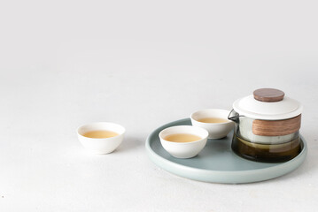 Chinese tea set , modern crystal pot and ceramic bowl cup with green tea on a try at white backgrounds, copy space