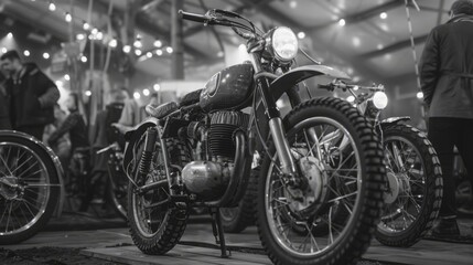 A black and white photo of a motorcycle with a man standing behind it