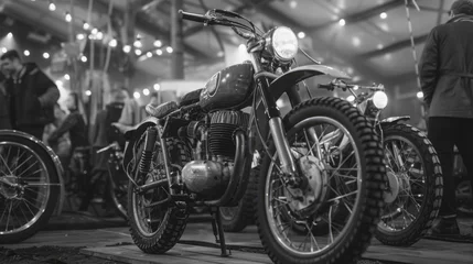 A black and white photo of a motorcycle with a man standing behind it