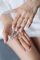 Woman touches the earring in the ear with her fingers. Close-up shot of female face and hand with black french manicure.