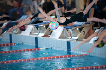 Swimmer girls start from the starting table in the pool