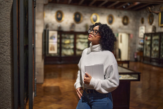 Woman visitor in the historical museum looking at art object.
