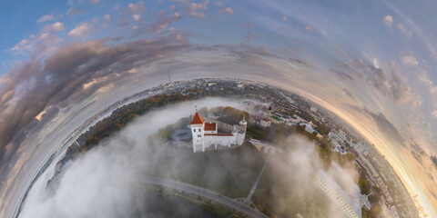 Aerial view from high altitude tiny planet in morning sky with clouds overlooking old town with...
