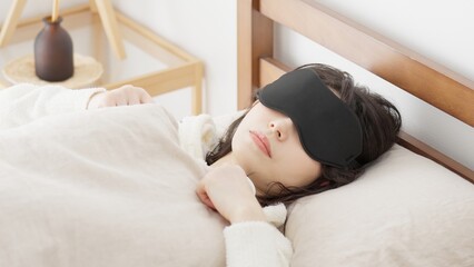 明るい部屋でアイマスクを付けて寝る女性