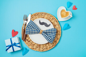 Table setting for Father's day breakfast with heart shape coffee cup, plate and gift box on blue...