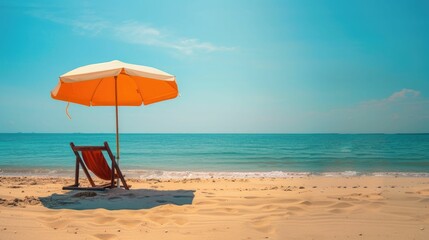 A chair and an umbrella provide shade on the sandy beach, with the azure sky reflecting in the crystal clear water of the oceanic coastal landforms AIG50