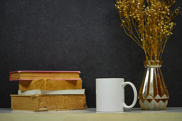 white coffee mug , white porcelain mug mock up on wood table with gypsophila flowers vase and books