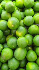 Close up pile of tasty fresh limes sold at the market as a background.