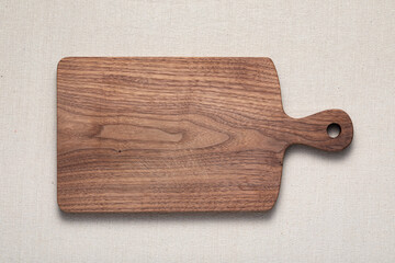 Handmade walnut wood cutting board with traces of use laid on burlap. Wood cutting board with knife...