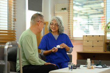 Smiling female general practitioner explaining medicine dosage to senior patient during home visit