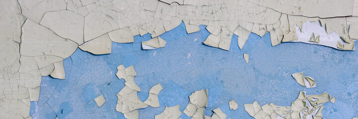 Fototapeta premium Peeling paint on the wall. Panorama of a concrete wall with old cracked flaking paint. Weathered rough painted surface with patterns of cracks and peeling. Wide panoramic texture for grunge background