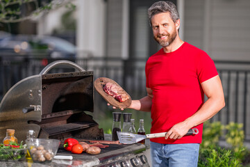 The Grill. Barbecue. Man Roasting and grilling food. Man hold cooking utensils barbecue. Roasting...