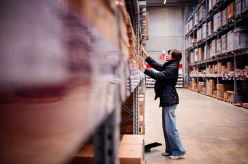 Young woman in motion, reaching out to a shelf in a warehouse. The blur effect emphasizes her swift...