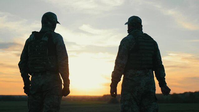 Greetings from the soldiers of the Ukrainian army. War in Ukraine. Two soldiers salute each other at sunset.