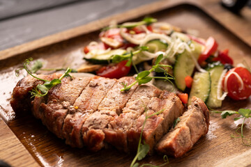 Grilled sirloin beef meat steak with vegetables on wooden board. close-up. Top view.