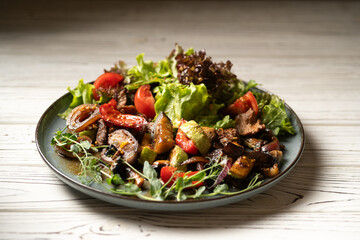 hot salad with beef fillet and grilled vegetables served on a plate on a light table in a restaurant
