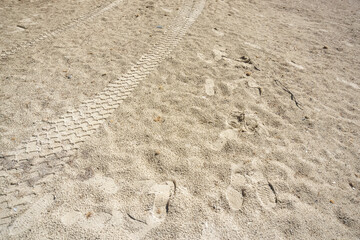 Fussabdrücke und Reifenspuren im Sand