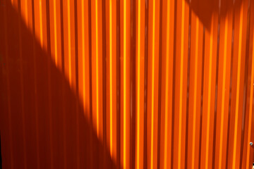The orange steel metal wall has a shadow texture background