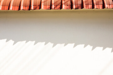 A red roof with a white wall in the background