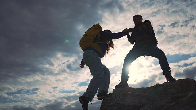 Mountain journey, two people travel. Silhouette helping hand concept. Adventurous climb, team travel trust. Travelers reach summit, teamwork in nature. People trekking mountain, inspiring travel shot.