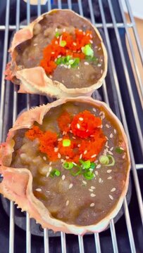 Kanimiso (miso crab kani) is a popular grilled Japanese seafood dish made from miso and crab meat mixed with crab shells grilled on a charcoal grill and topped with salmon roe and scallions.- video