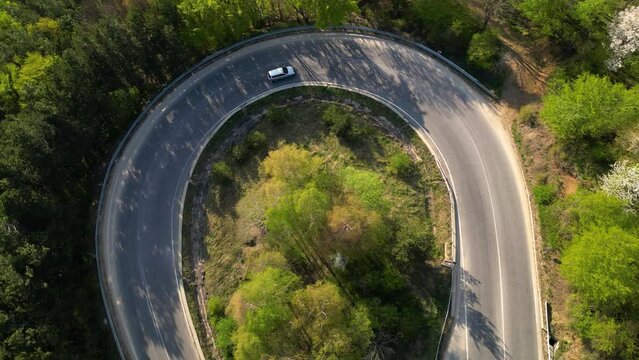 Mountain road seen from a drone. High angle fotoage of vehicles traversing a picturesque mountain curve of Shipka pass in Bulgaria. A busy European forrest road seen from above. Cars trucks driving

