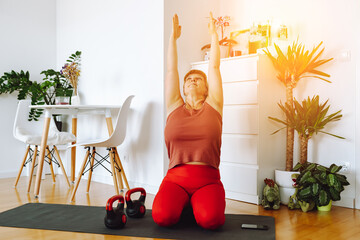 middle-aged woman does yoga in bright spacious room with house plants