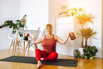 middle-aged woman does yoga in bright spacious room with house plants