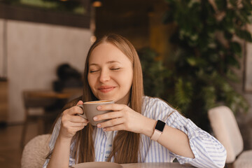 Portrait of gorgeous smiling lady with closed eyes smelling, enjoying of coffee and drinking...