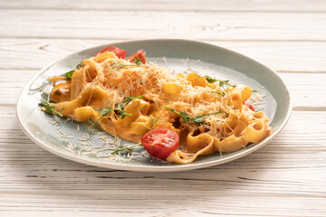 Traditional Italian fettuccine pasta with tomato sauce, tomato slices and green leaves