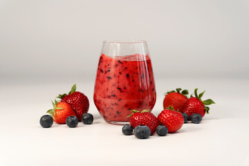 Smoothie mit Erdbeere Heidelbeere Kokosmilch Smoothie in einem Glas mit Erdbeeren und Heidelbeeren im Vordergrund mit weißem Hintergrund