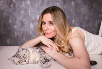 portrait of a pretty girl with a gray cat at home.