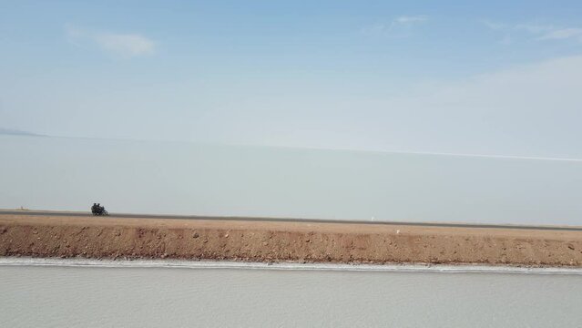 Aerial drone footag ef a bike riding in the middle of the ocean in road to heaven in gujrat