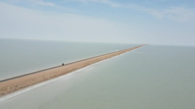 Aerial drone footag ef a bike riding in the middle of the ocean in road to heaven in gujrat